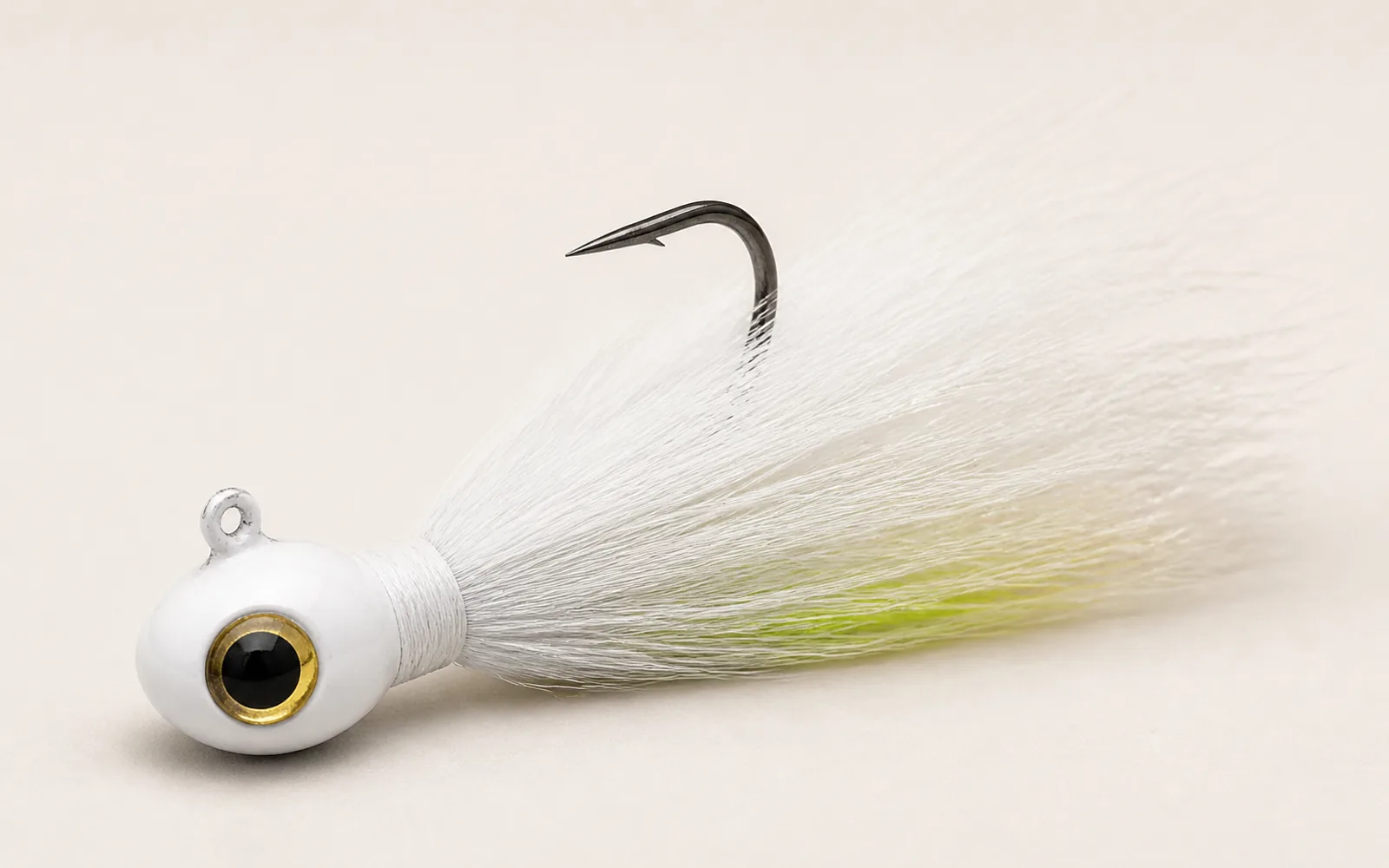 White power bucktail jig with painted lead head, large eye, single hook, and chartreuse accent hair